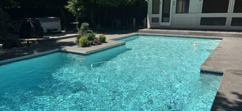 Sparkling clean backyard pool with a raised spa after weekly service in Frisco
