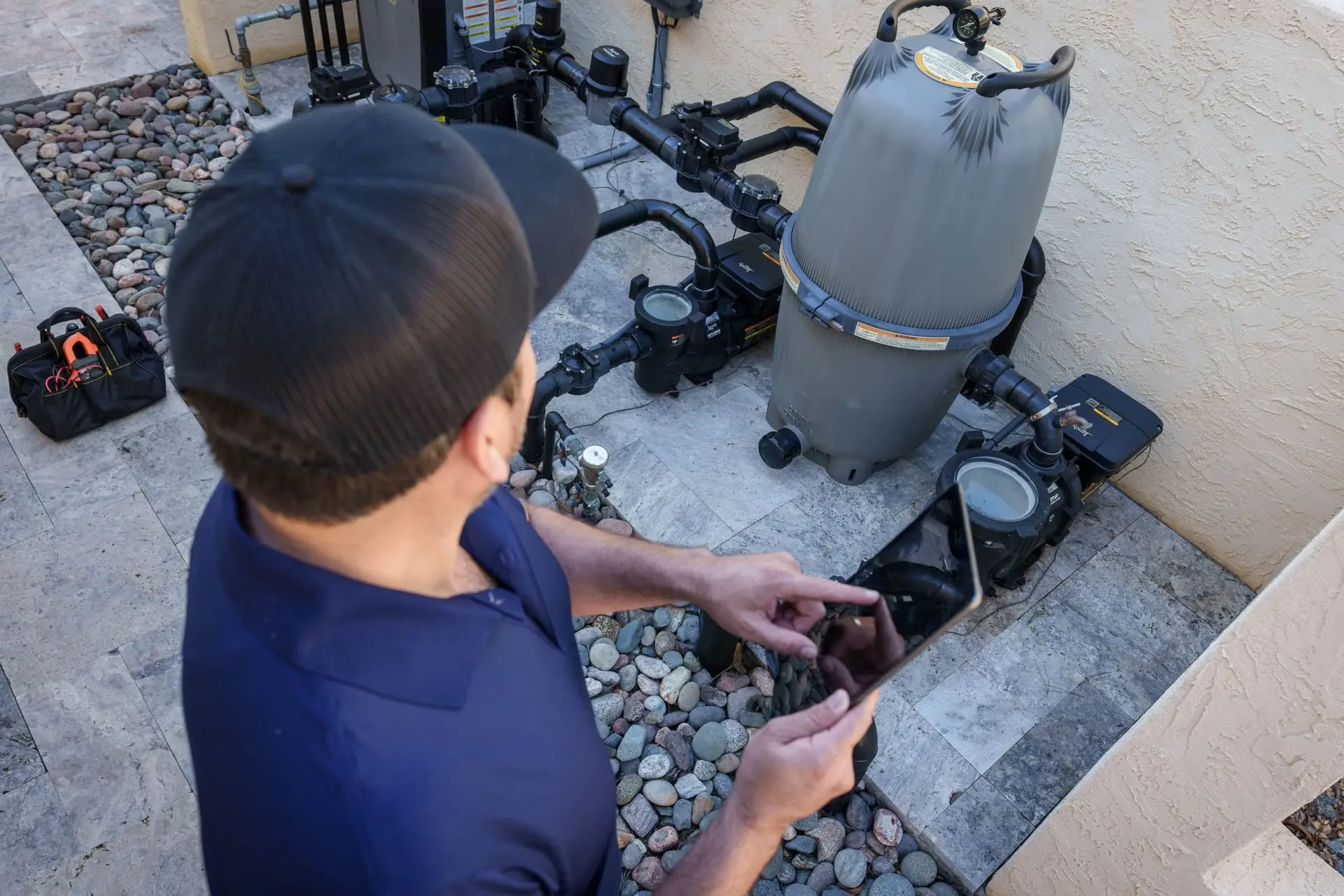 NorTex Pools technician inspecting a pool pump and filter on an equipment pad