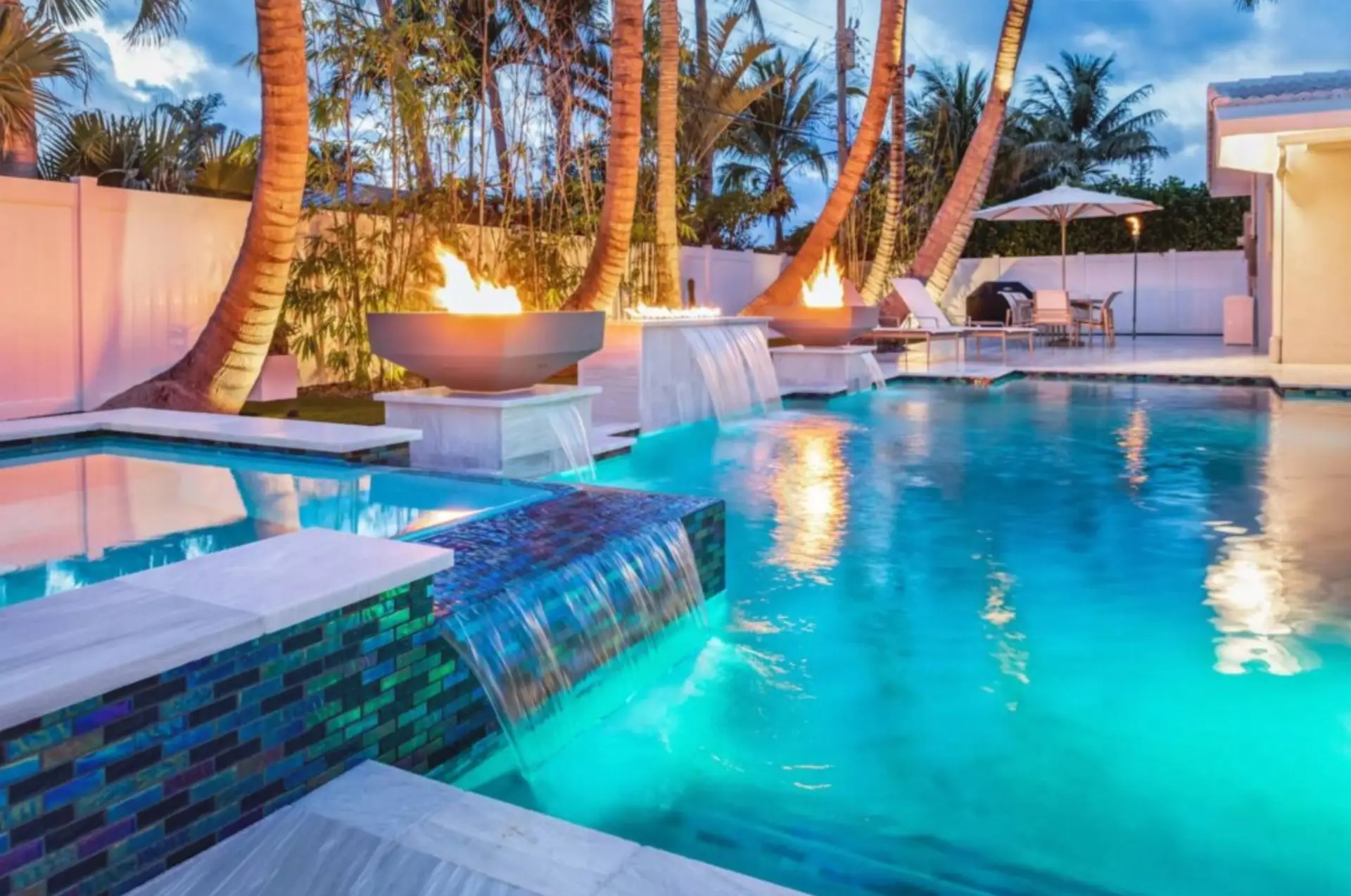 Luxury backyard pool with fire feature and palm trees at sunset