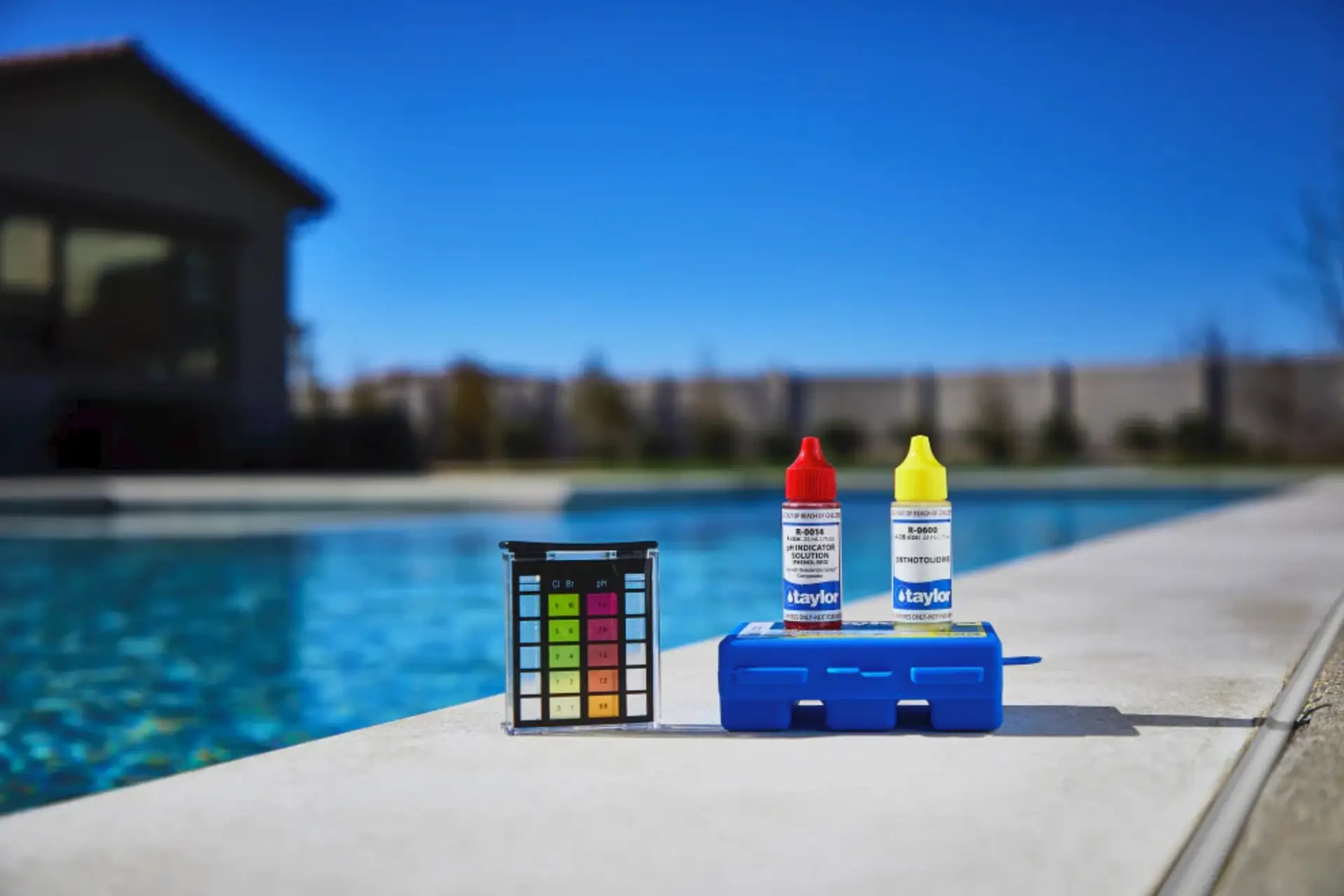 Pool water test kit and reagent bottles on the edge of a clear pool