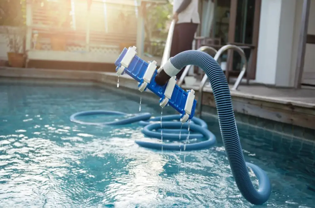 Pool vacuum hose cleaning a clear backyard pool