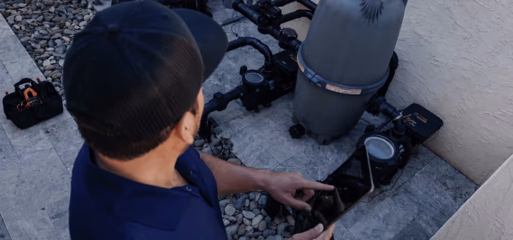 NorTex Pools technician inspecting a pool pump and filter on an equipment pad