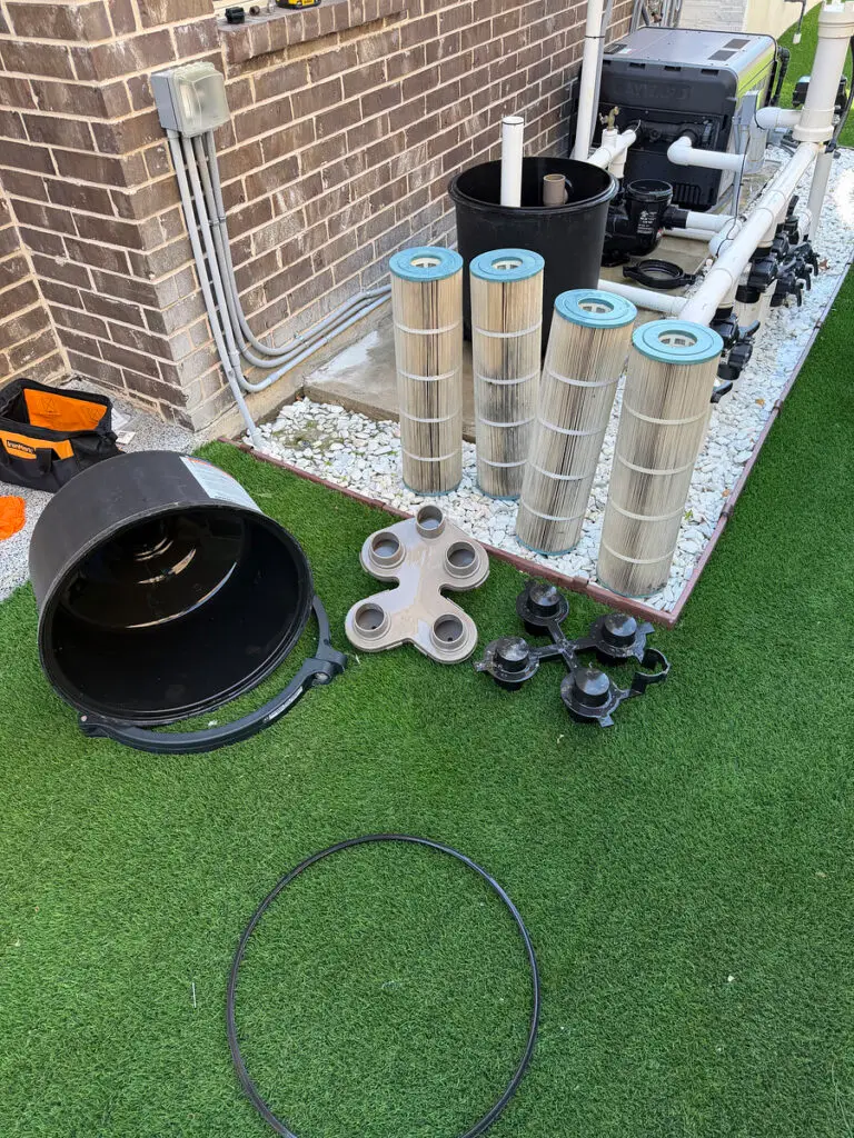 DE filter grids and parts laid out on the lawn during a filter repair