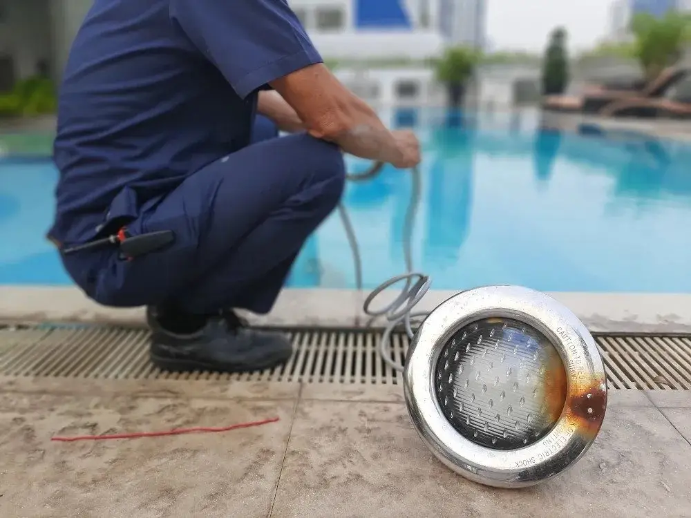 NorTex Pools technician replacing an underwater pool light at poolside